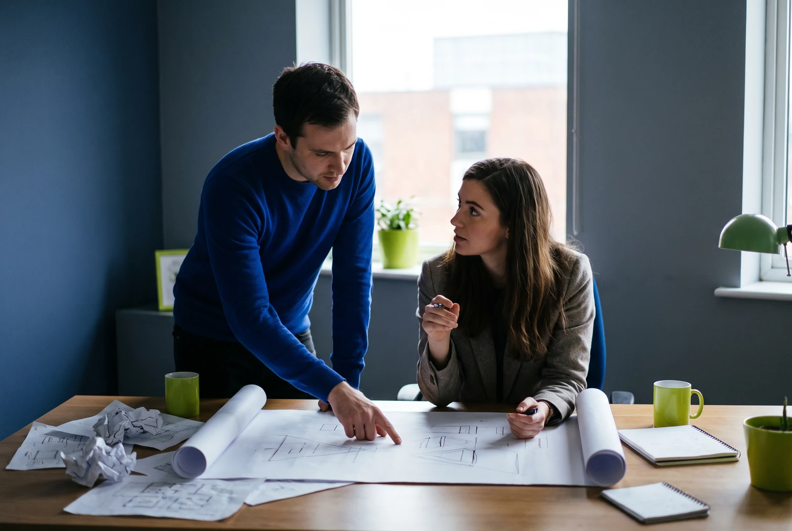 Two people discussing a drawn plan across a desk